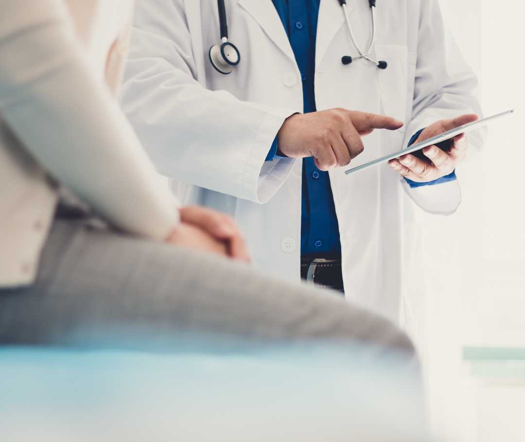Kompetenznetzwerk Nuklearmedizin Ein Arzt zeigt seiner Patientin ihre Befunde auf einem Tablet
