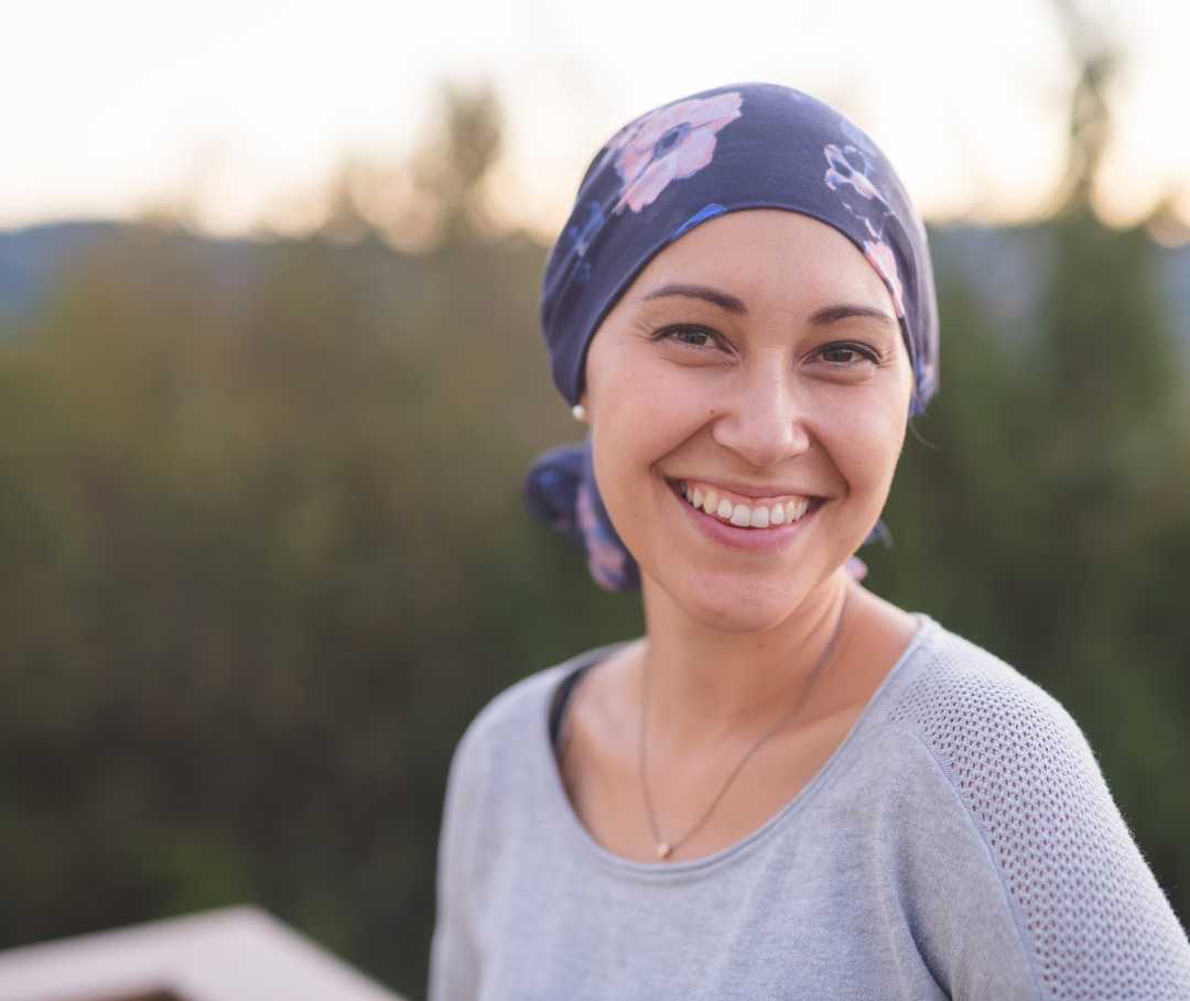 Kompetenznetzwerk Nuklearmedizin: Therapie Eine Patientin mit um den Kopf gebundenem Tuch lacht in die Kamera