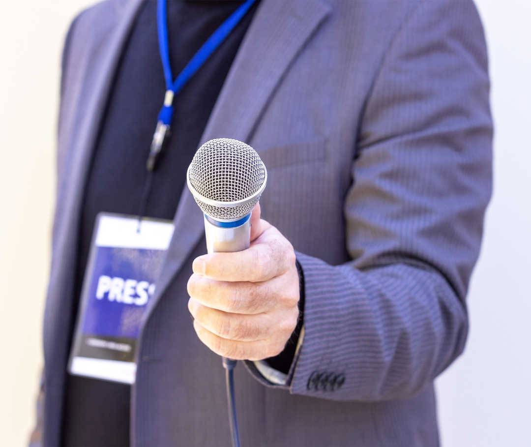 Ein Mann hält ein Mikrofon in die Kamera.